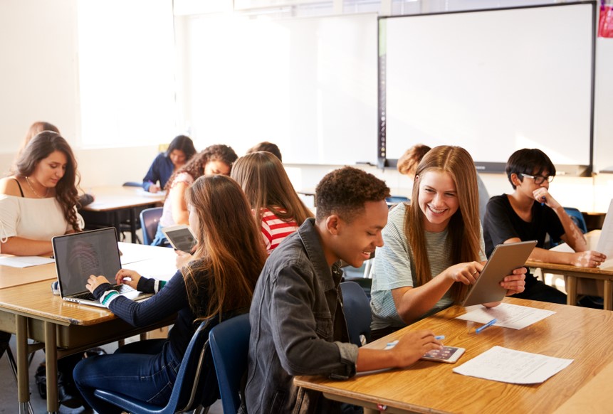 Jugendliche Schüler*innen arbeiten in der Schule mit digitalen Endgeräten zusammen.