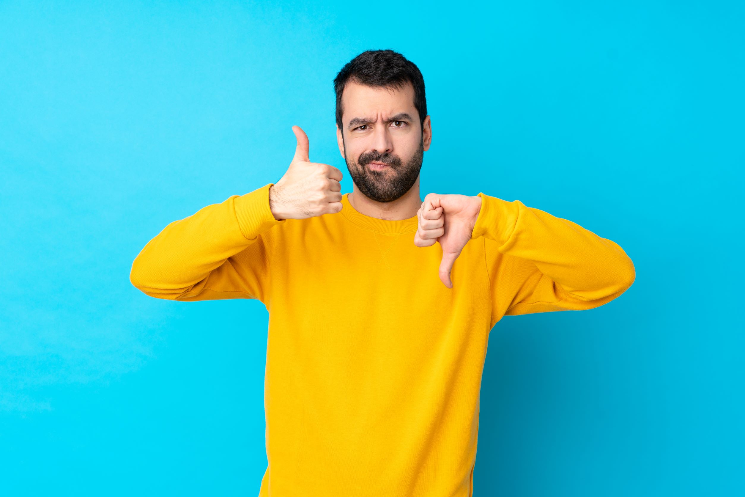 Mann hält einen Daumen hoch, einen Daumen runter