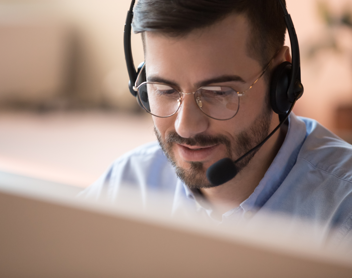 Ein Mann mit Headset sitzt vor einem Computerbildschirm und arbeitet.