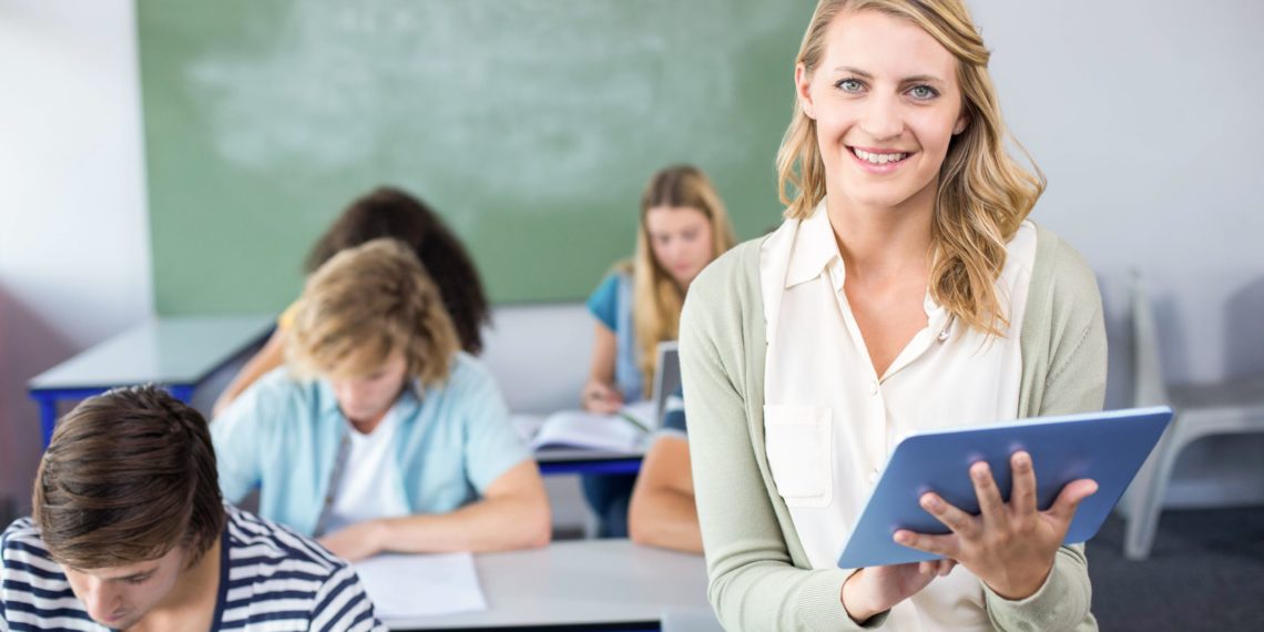 Lächelnde Lehrerin mit Tablet in Klassenraum