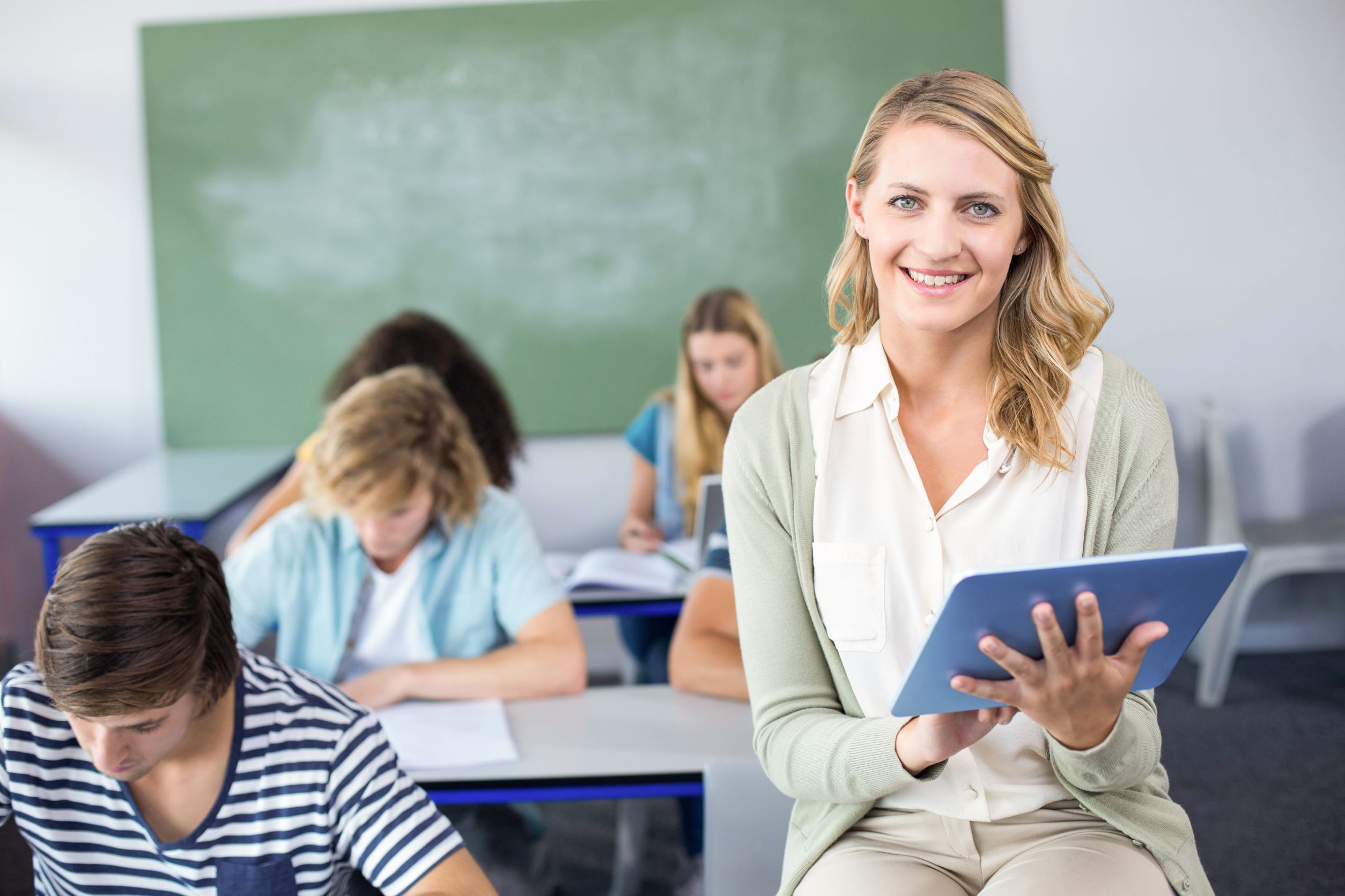 Lächelnde Lehrerin mit Tablet in Klassenraum