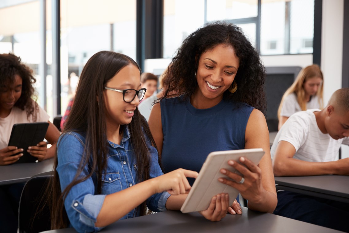 Eine Schülerin zeigt ihrer Lehrerin etwas auf dem Tablet-Computer.