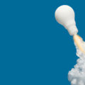 Das Symbolbild zeigt eine weiße Glühbirne, die wie eine Rakete in die Luft startet.